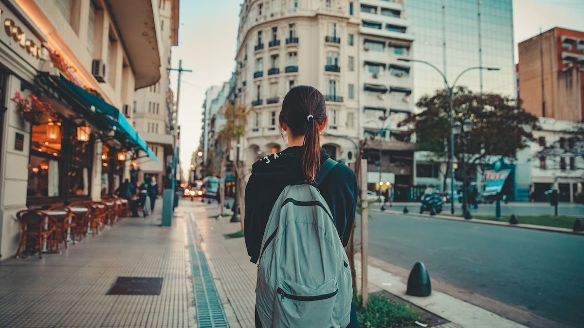A woman with a backpack walking down a vibrant street in San Nicolás, Buenos Aires, Argentina.